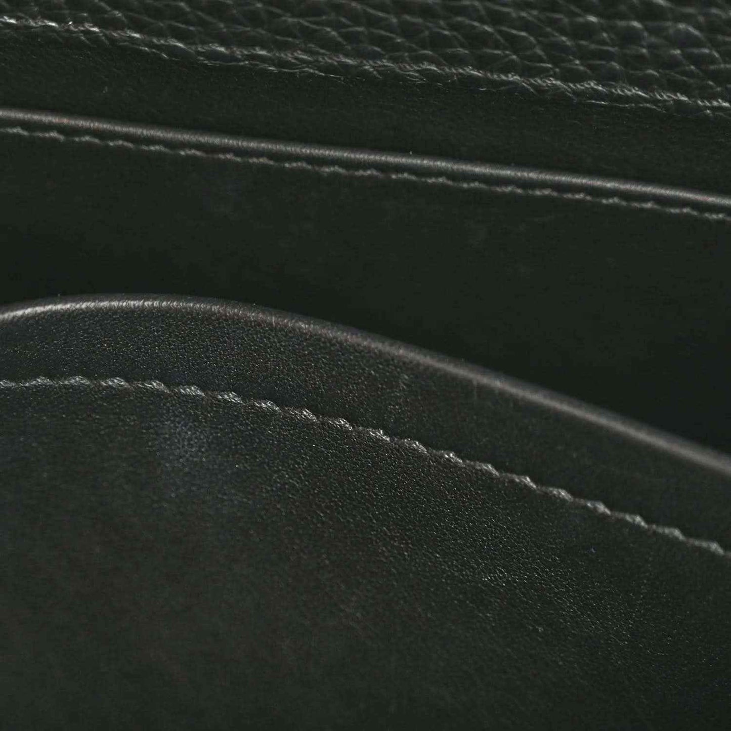 Close-up of black leather bag seam and edge stitching with pebbled texture
