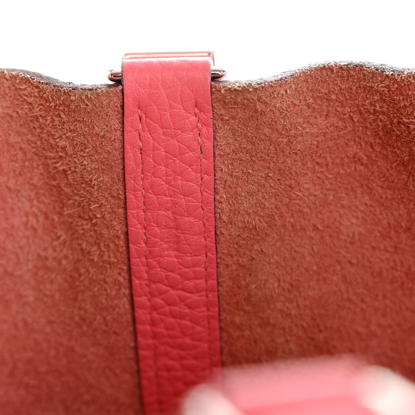 Pink leather strap with metal buckle clasp at the tote edge