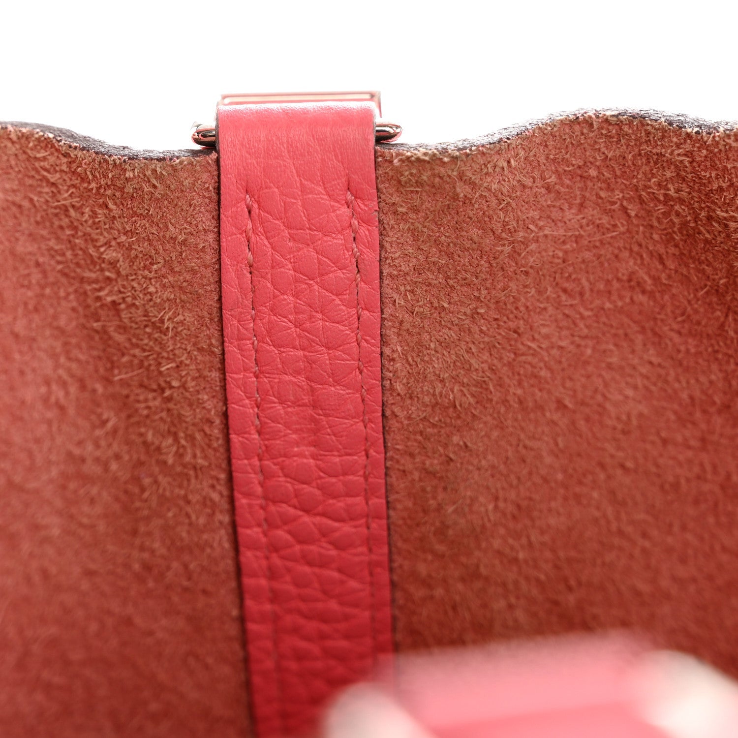 Pink leather strap with metal buckle clasp at the tote edge