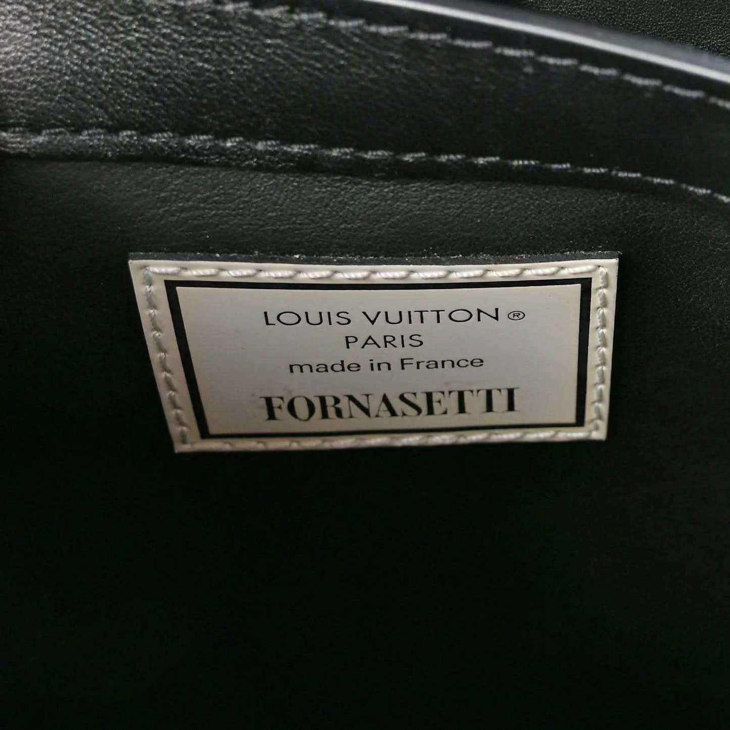 Close-up of handbag interior label reading Louis Vuitton and Fornasetti