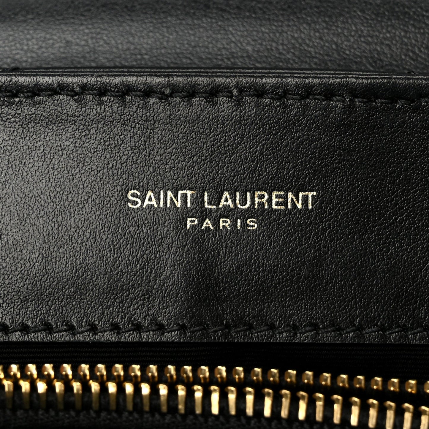 SAINT LAURENT PARIS text on black leather with gold zipper edge detail.