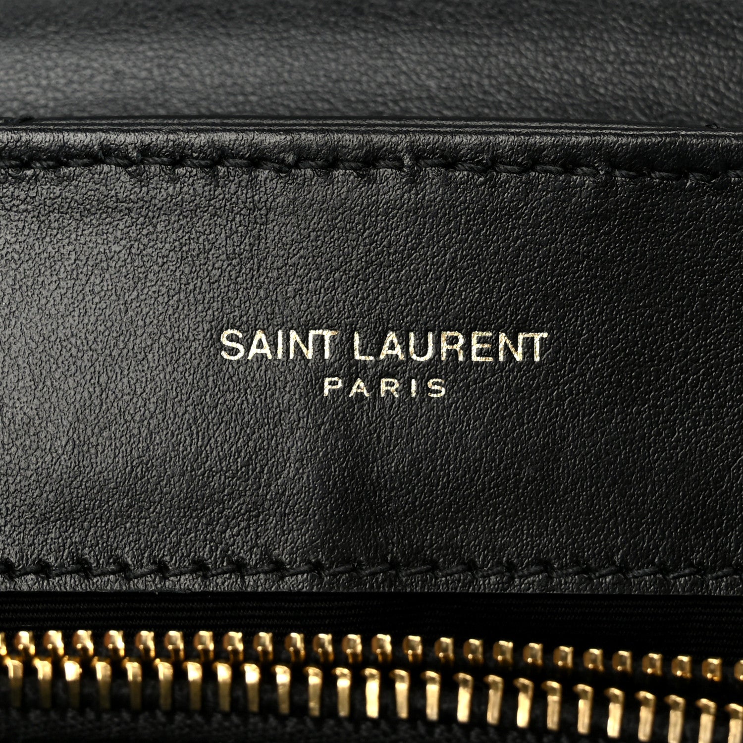 SAINT LAURENT PARIS text on black leather with gold zipper edge detail.