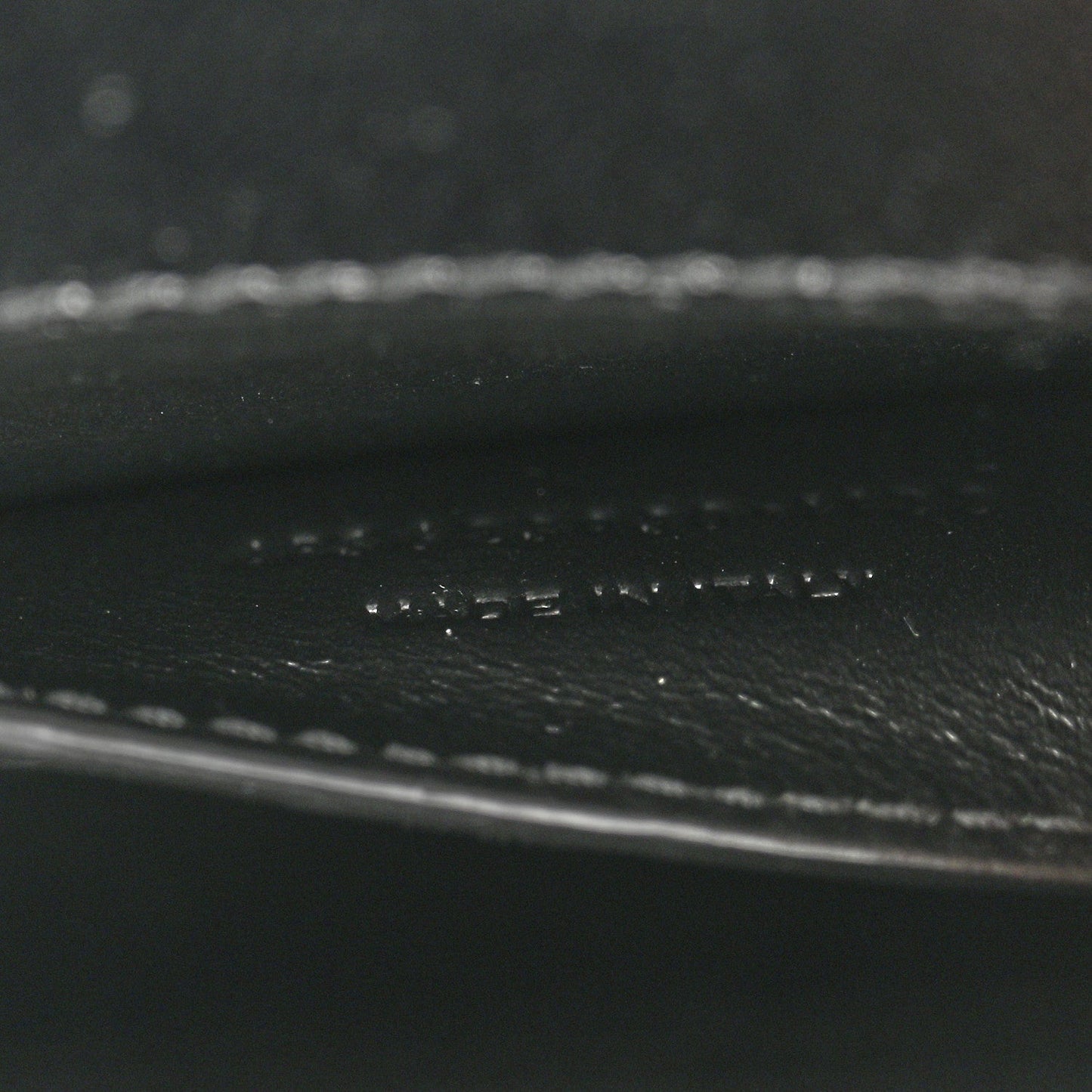 Black leather close-up showing pebbled texture and stitched trim.
