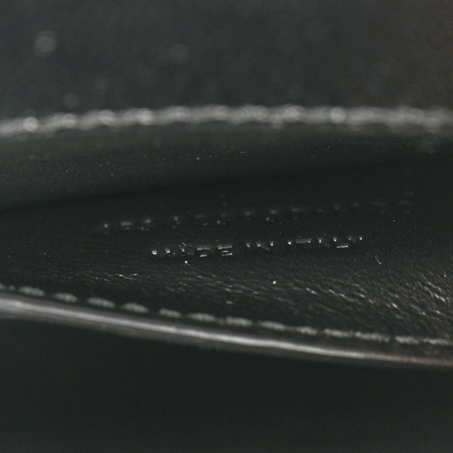 Black leather close-up showing pebbled texture and stitched trim.