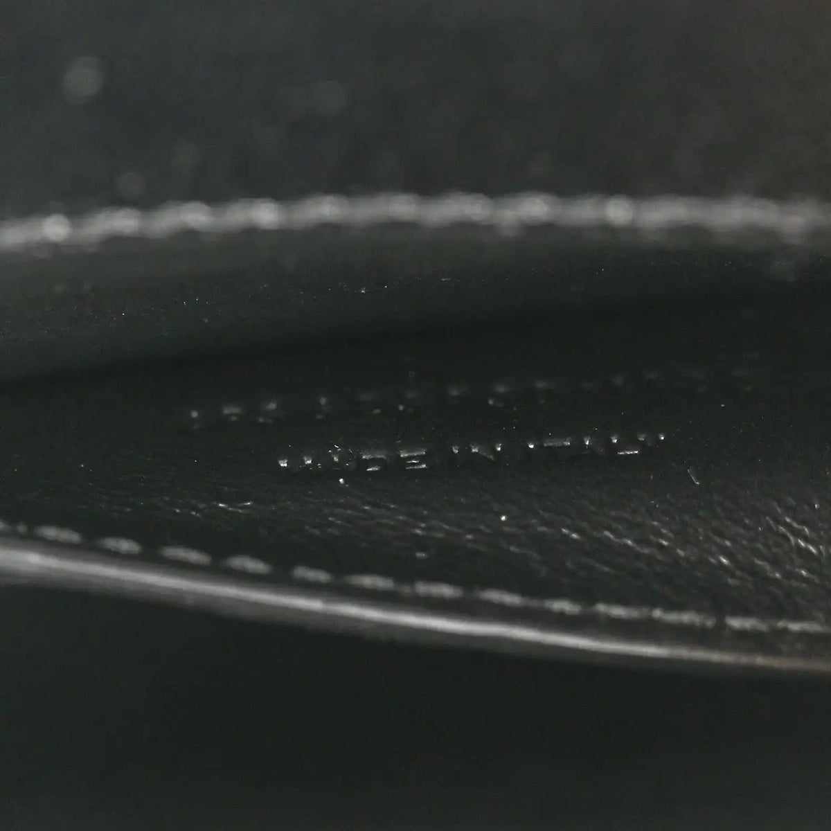 Black leather close-up showing pebbled texture and stitched trim.