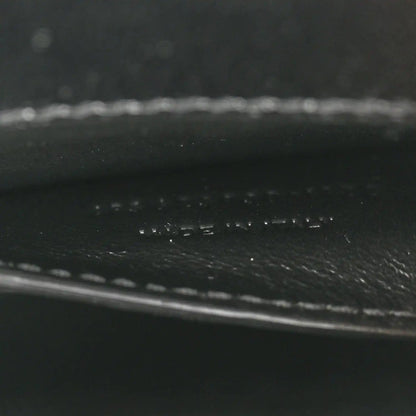 Black leather close-up showing pebbled texture and stitched trim.