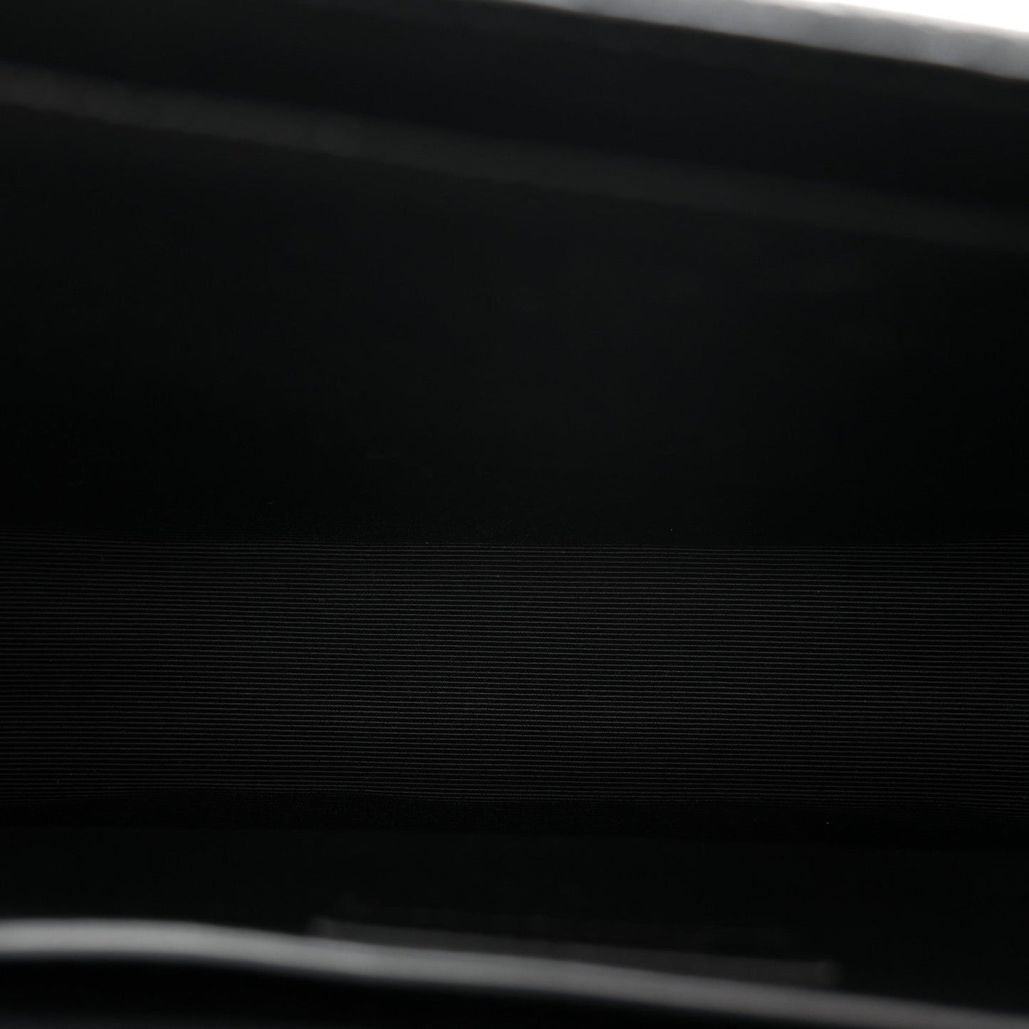 Black leather satchel bag close-up with textured grain and stitched edge