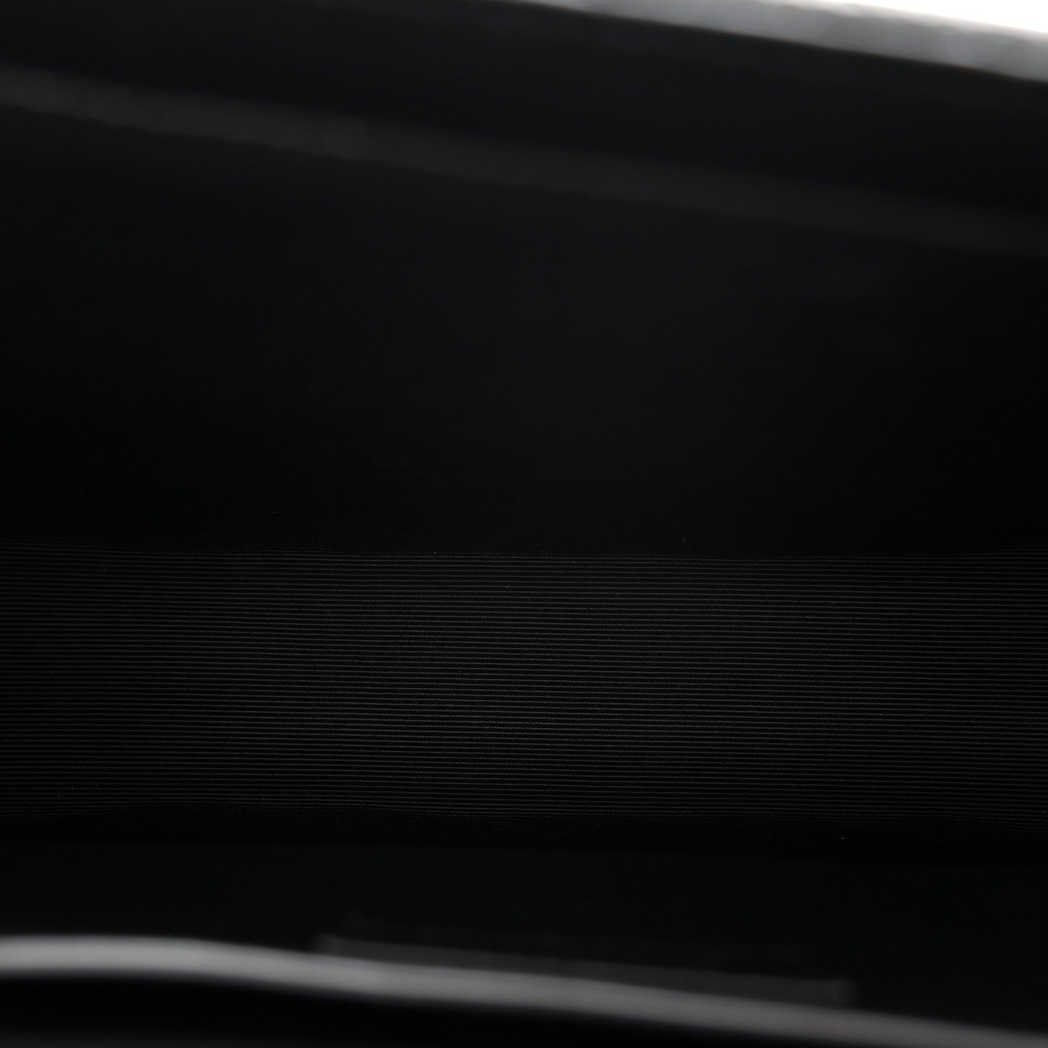 Black leather satchel bag close-up with textured grain and stitched edge