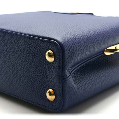 Blue pebbled leather handbag corner with gold-tone studs and curved edge seam