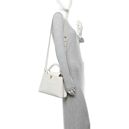 White top-handle bag worn on shoulder with crossbody strap and gold hardware