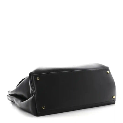 Black leather medium shoulder bag base view with gold-tone feet and curved side panels.