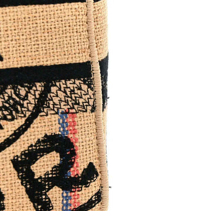 Beige jute tote bag with black embroidered graphic and multicolor thread detail