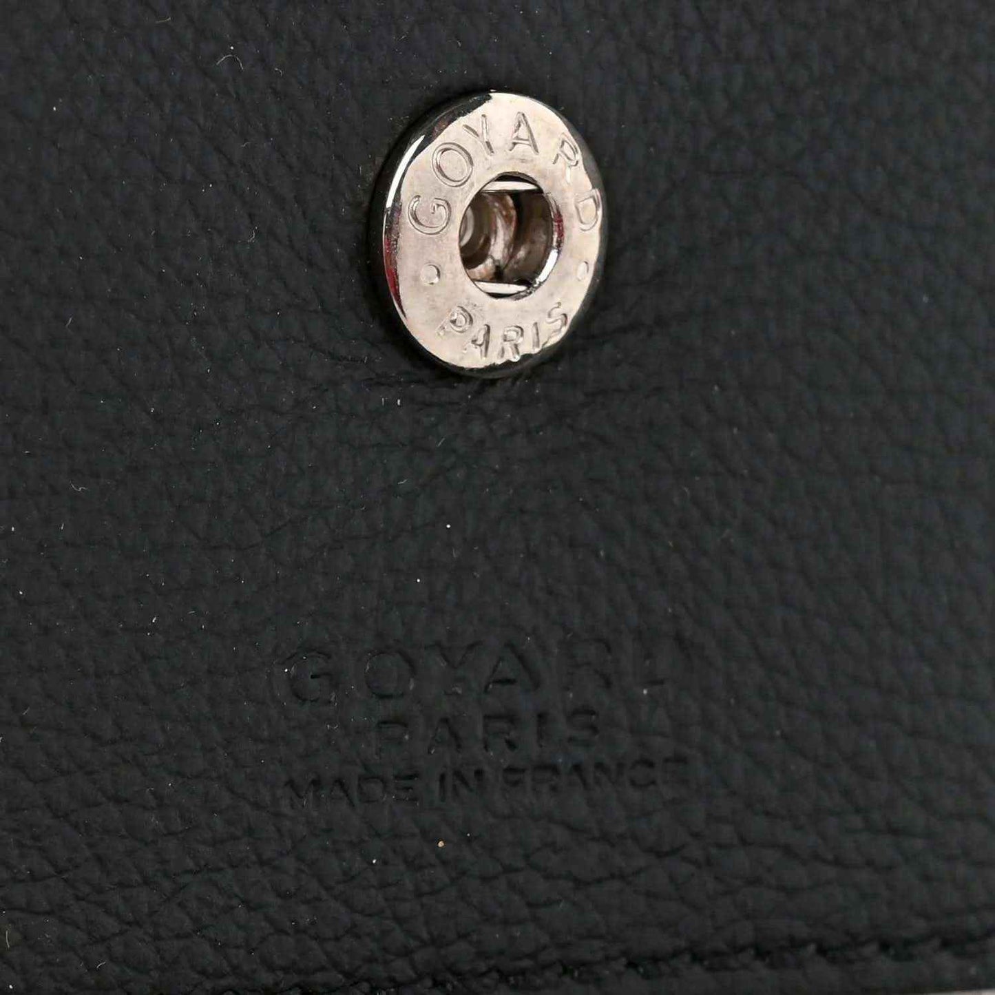 Metal brand hardware on black textured leather