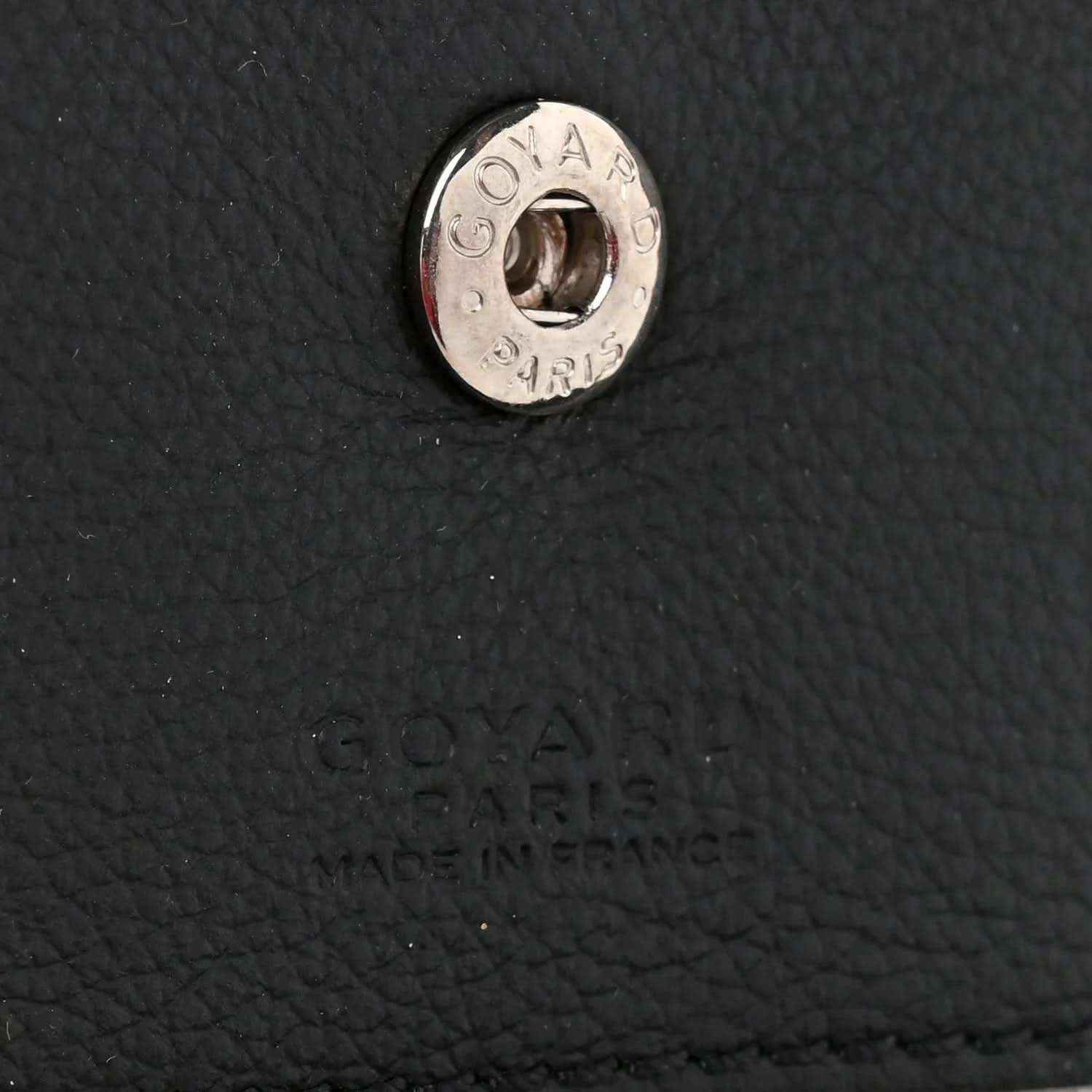 Metal brand hardware on black textured leather