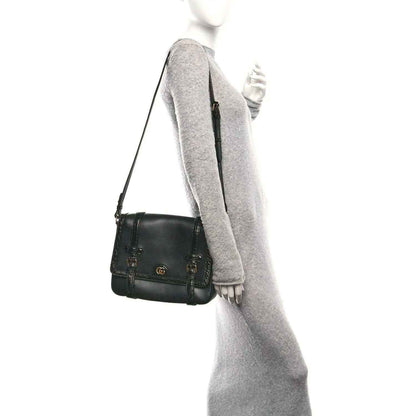 Black leather medium crossbody messenger bag with gold-toned hardware and double buckles