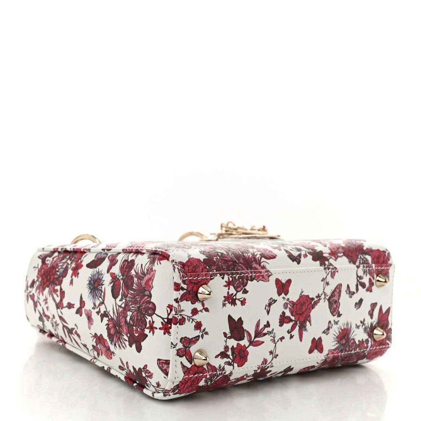 Small floral handbag with zip top, white exterior with red blossoms, and gold feet