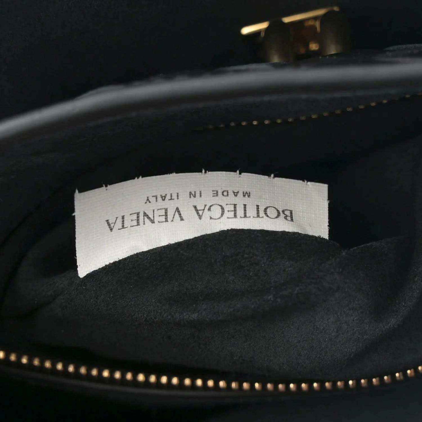 Black leather bag interior with fabric brand label and gold-tone zipper trim.