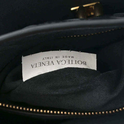 Black leather bag interior with fabric brand label and gold-tone zipper trim.
