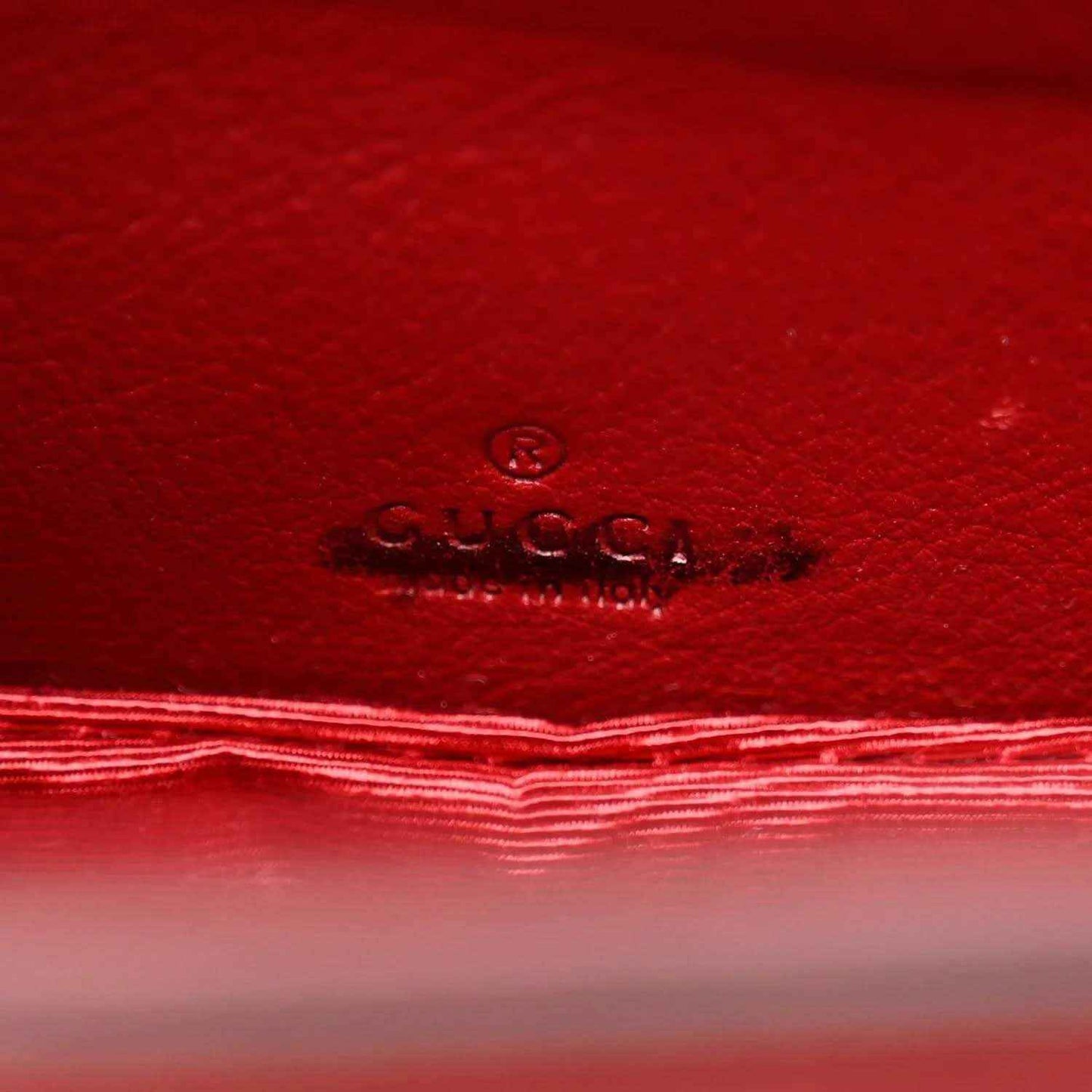 Red leather interior panel with embossed Gucci logo and stitched border.