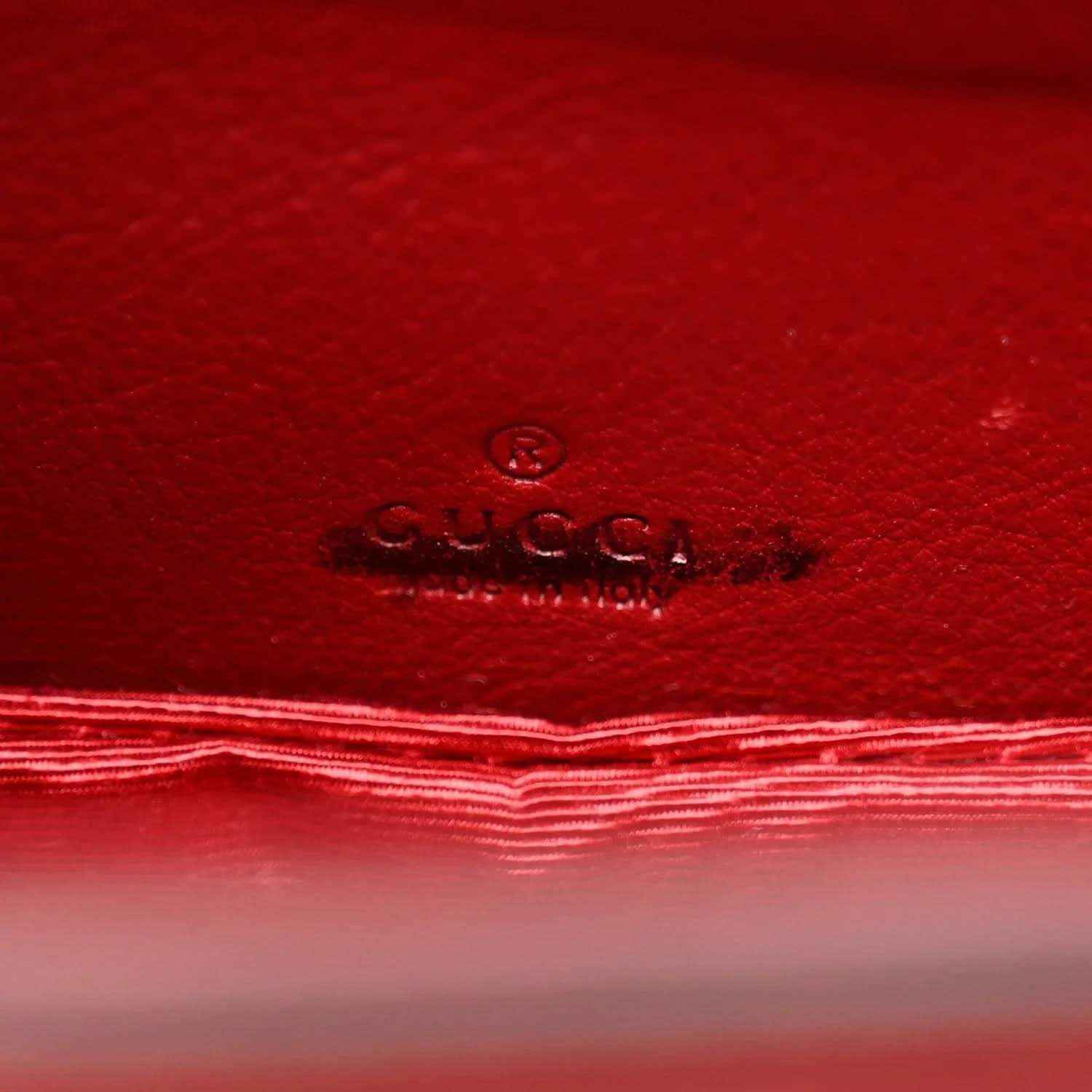 Red leather interior panel with embossed Gucci logo and stitched border.