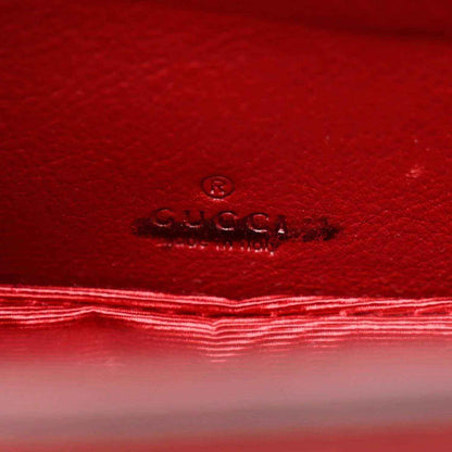 Red leather interior panel with embossed Gucci logo and stitched border.