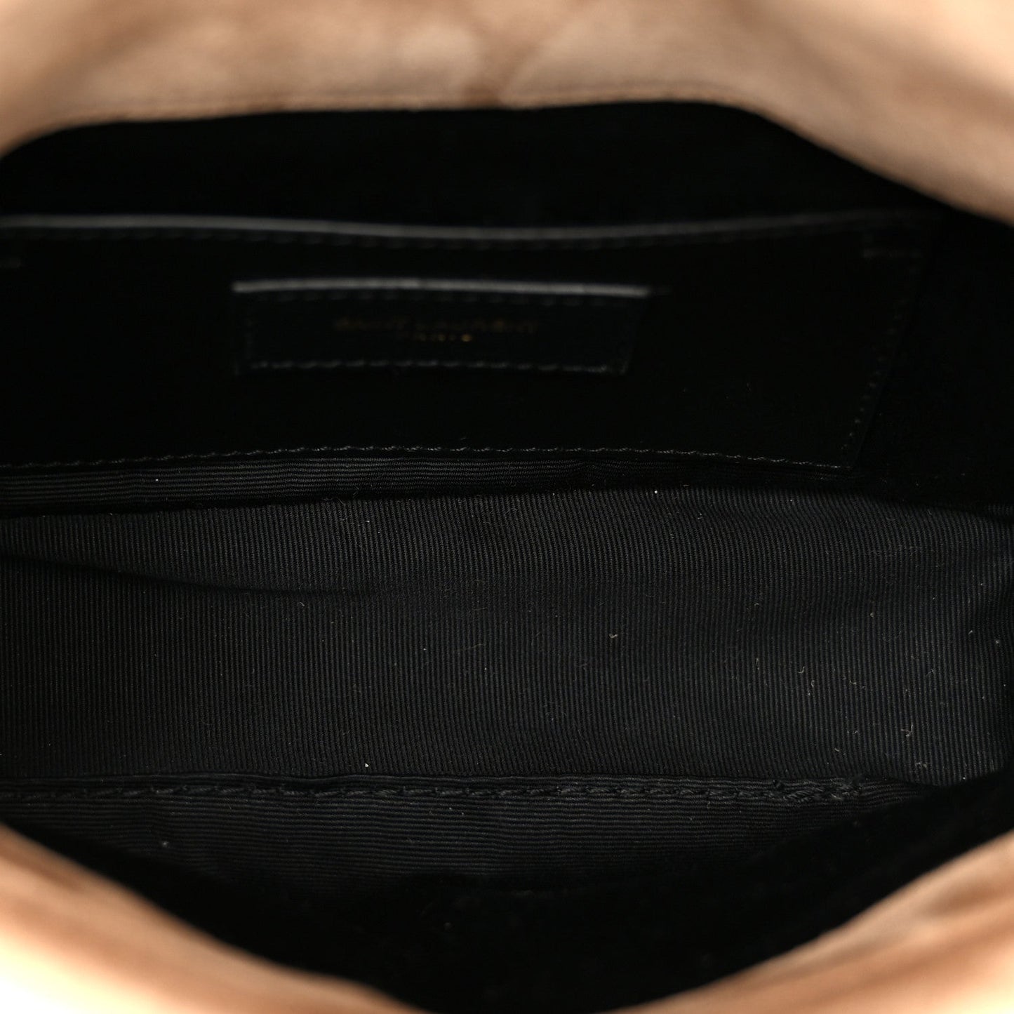 Black fabric interior of mini shoulder bag with stitched wall and top opening