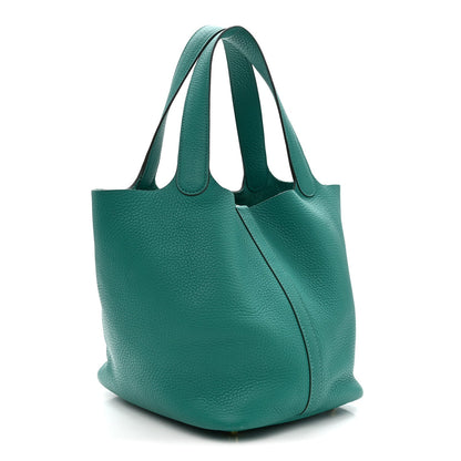 Green leather tote with curved silhouette, top handles, and side seam detail