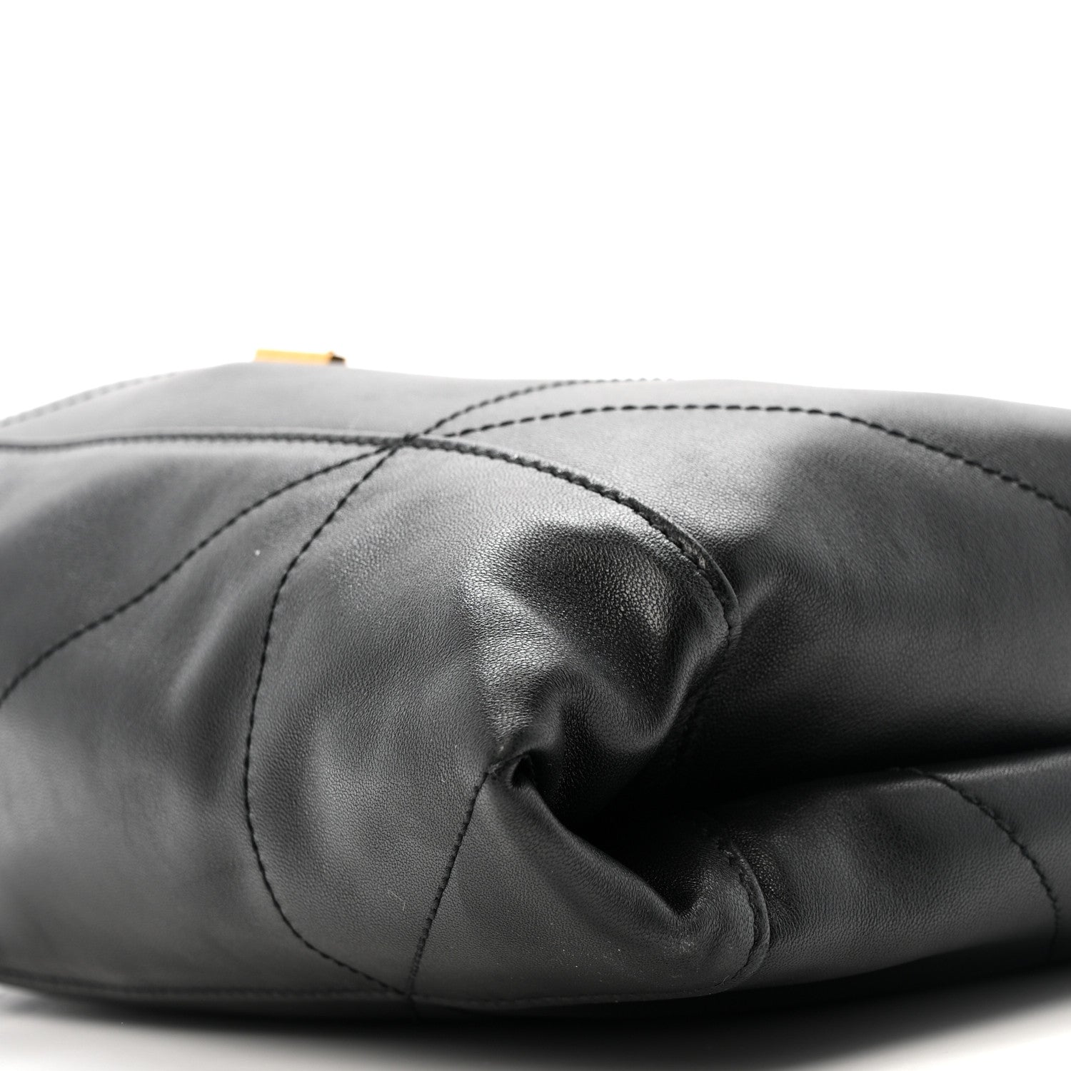Black quilted leather drawstring bag in folded drape with stitched panels close-up