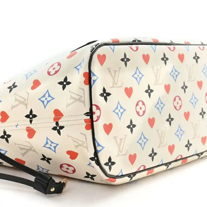 White monogram tote with multicolor heart print, black trim, and zip closure edge