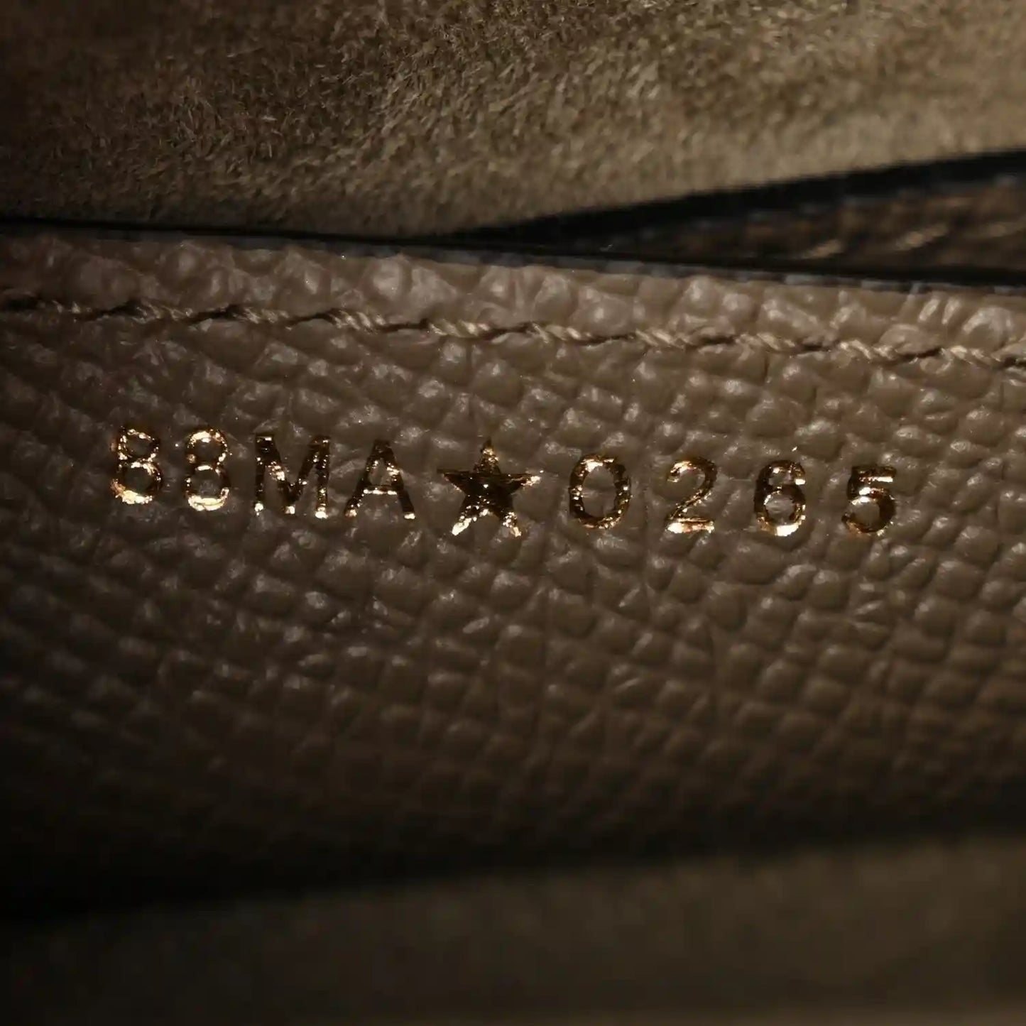 Close-up of small gold-tone text on dark green grained leather lining