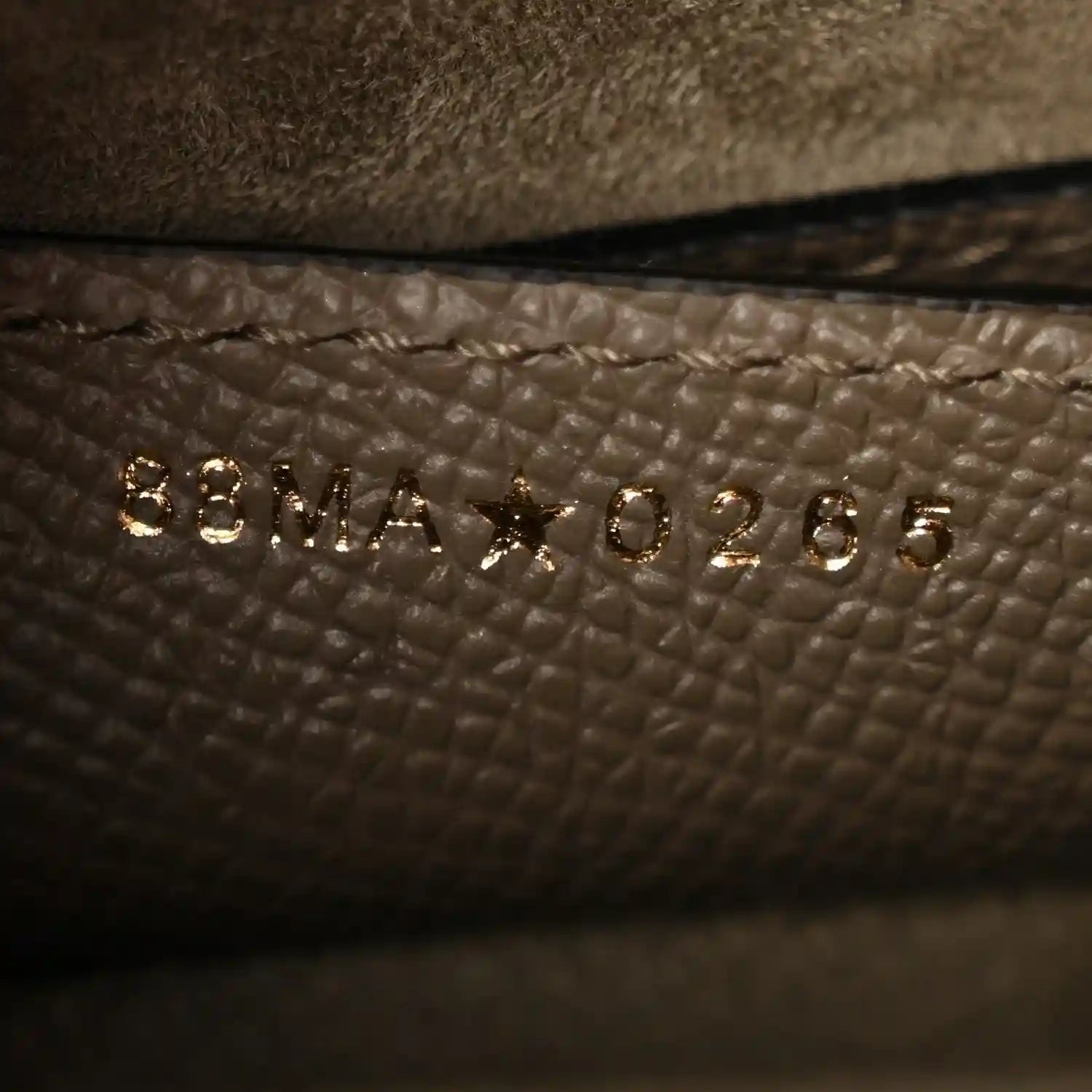 Close-up of small gold-tone text on dark green grained leather lining