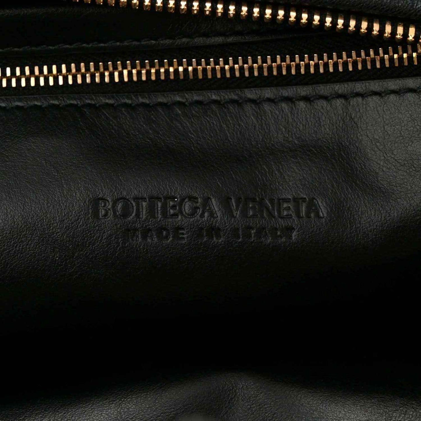 Black leather bag with engraved Bottega Veneta logo near zipper