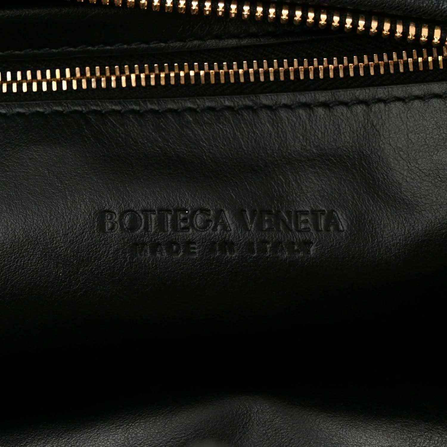 Black leather bag with engraved Bottega Veneta logo near zipper