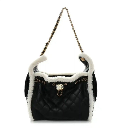 Black quilted handbag with white shearling lining, chain strap, and logo turn-lock