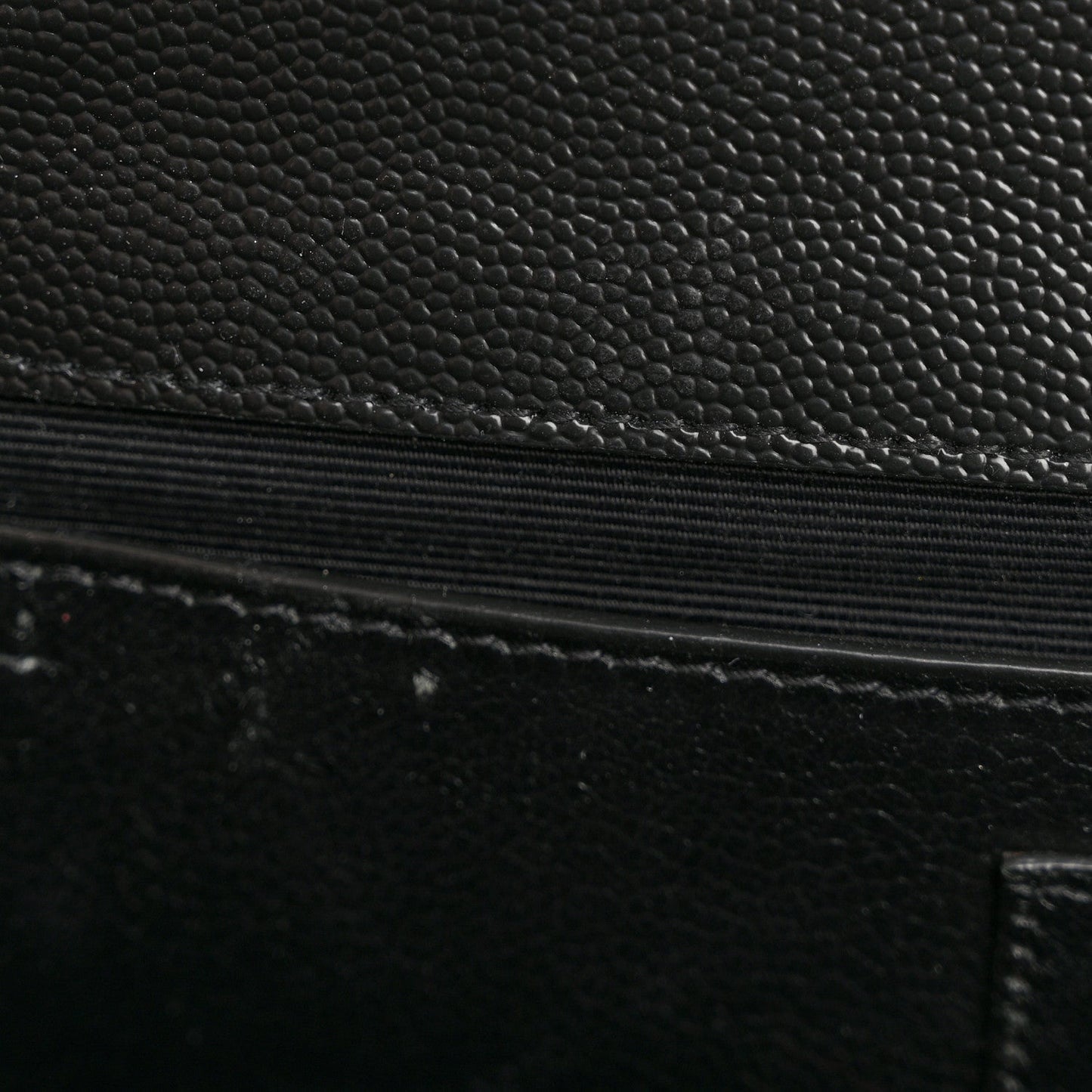 Quilted satchel leather detail with black textured finish and stitched edge