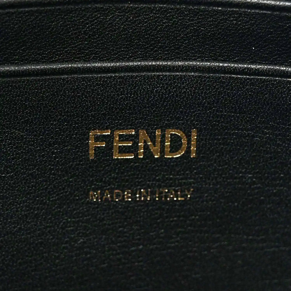 Black leather patch with FENDI lettering, close-up on mini baguette bag.