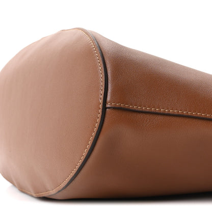 Close-up of tan-brown calfskin drawstring tote end with rounded shape and top stitch