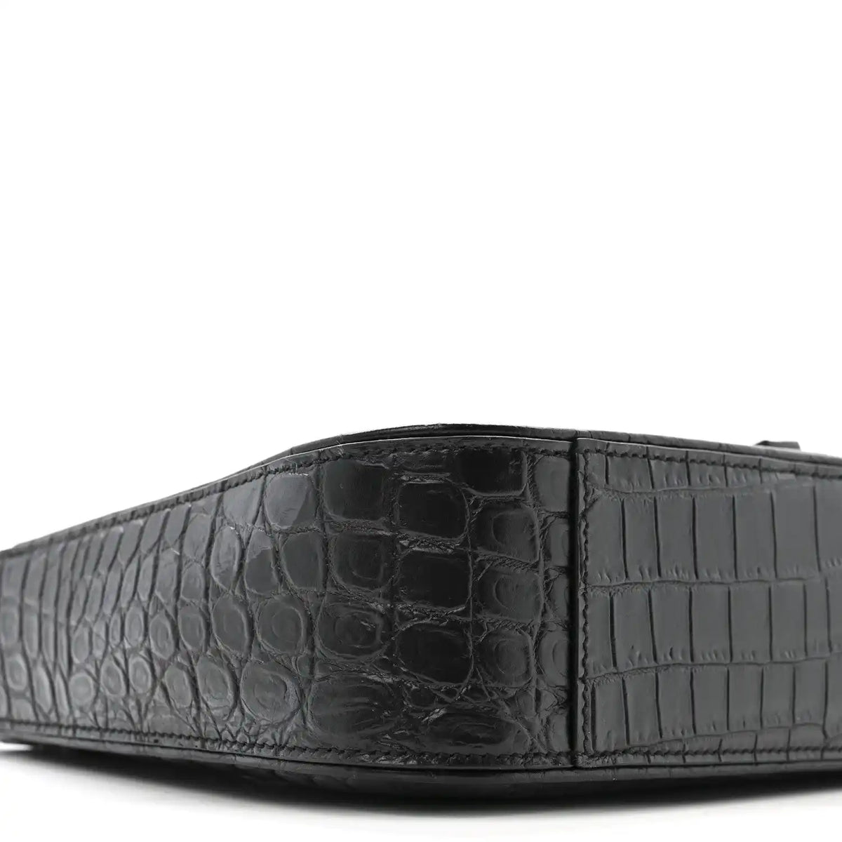 Close-up of bag front panel with crocodile-embossed texture and seams.