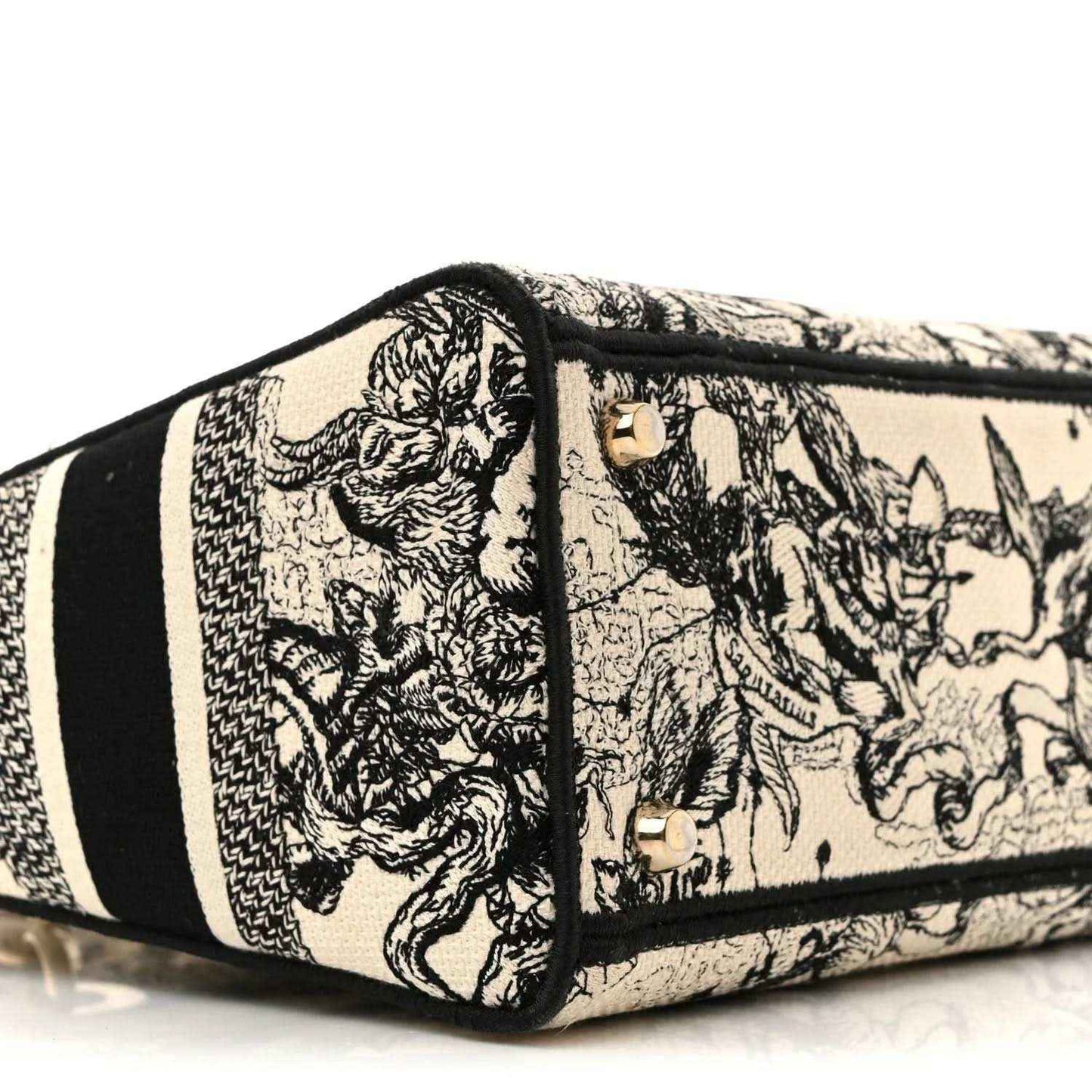 Toile-printed tote side panel with gold hardware studs and black trim stripe.