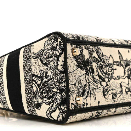 Toile-printed tote side panel with gold hardware studs and black trim stripe.