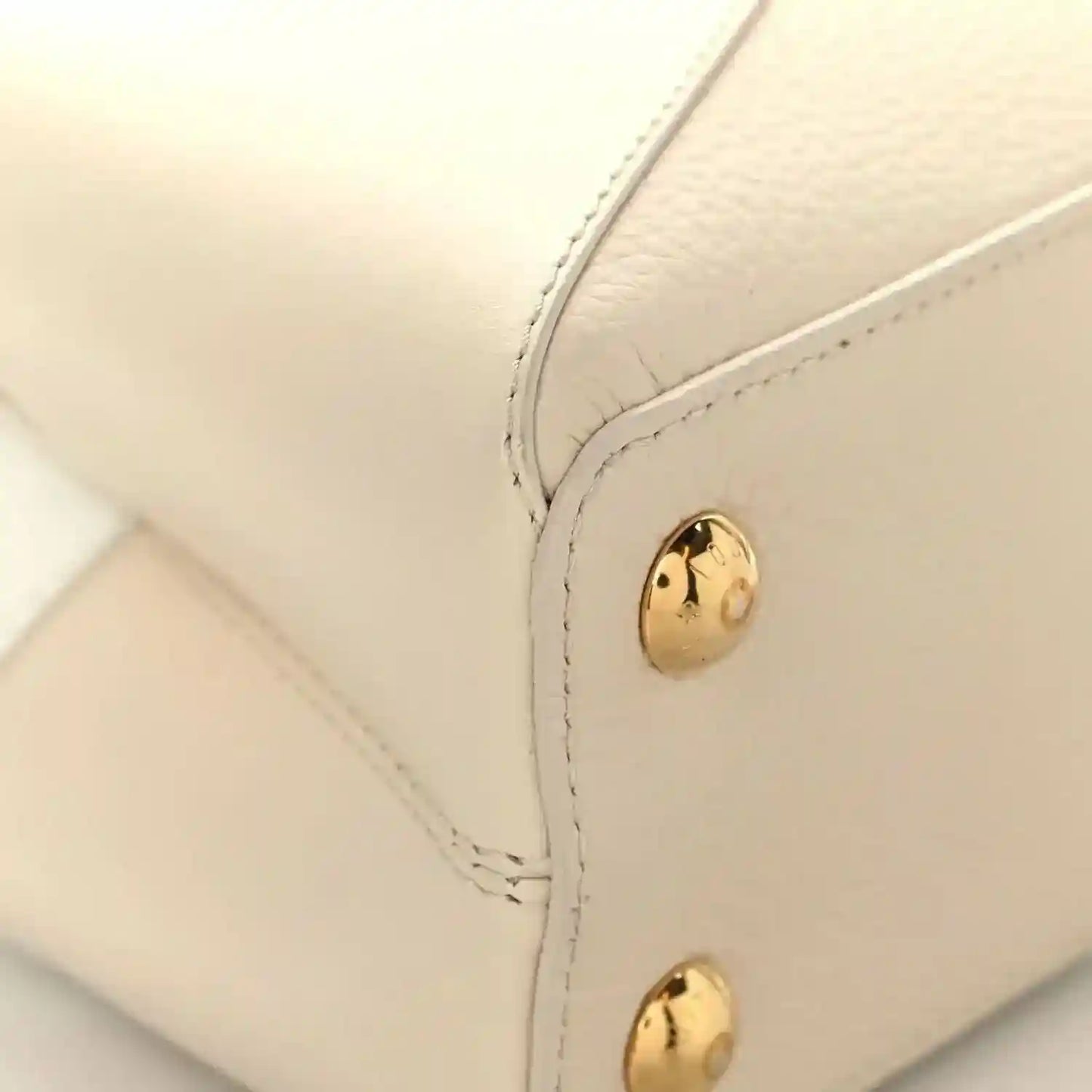 Cream leather handbag corner with gold snap button and neat contrast stitching