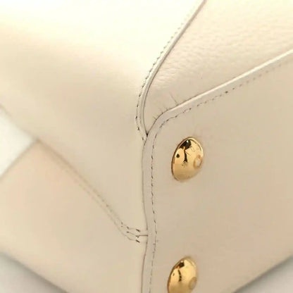 Cream leather handbag corner with gold snap button and neat contrast stitching