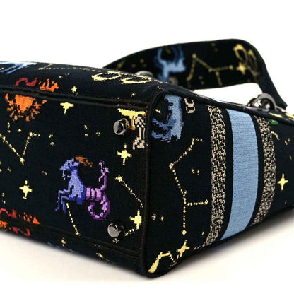 Side view of medium handbag with zodiac pixel print, blue stripe, and silver-tone hardware