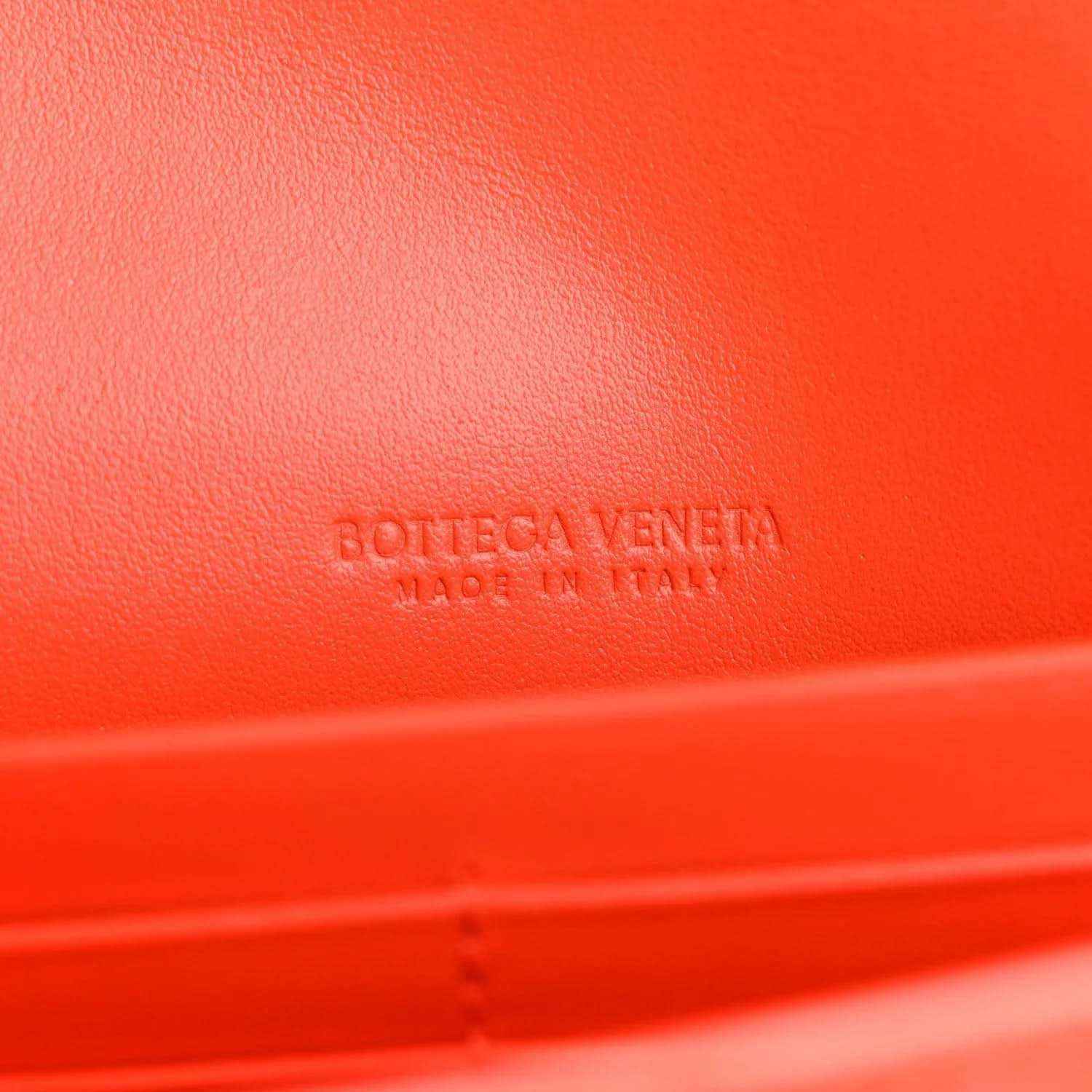 Orange leather clutch with embossed branding on the surface