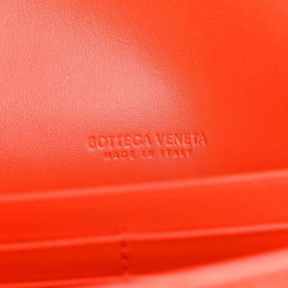 Orange leather clutch with embossed branding on the surface