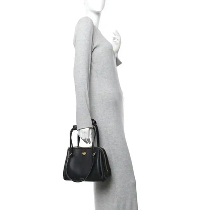 Small Madrid bag in black leather with short strap and gold zip, carried crossbody.