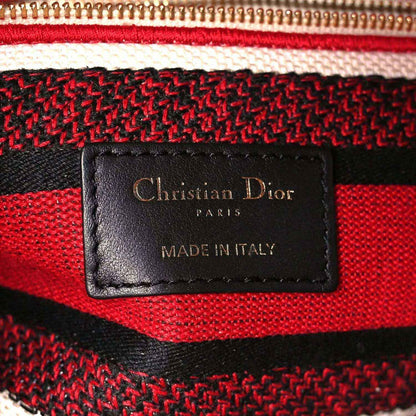 Leather brand patch on red and black striped canvas bag reading Christian Dior Paris
