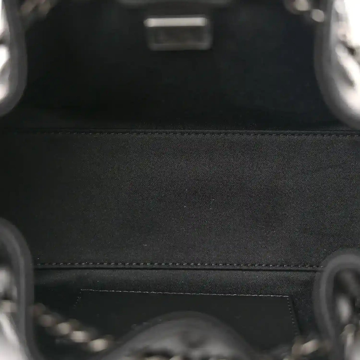 Black leather bag interior with stitched seam and metal hardware ring detail.