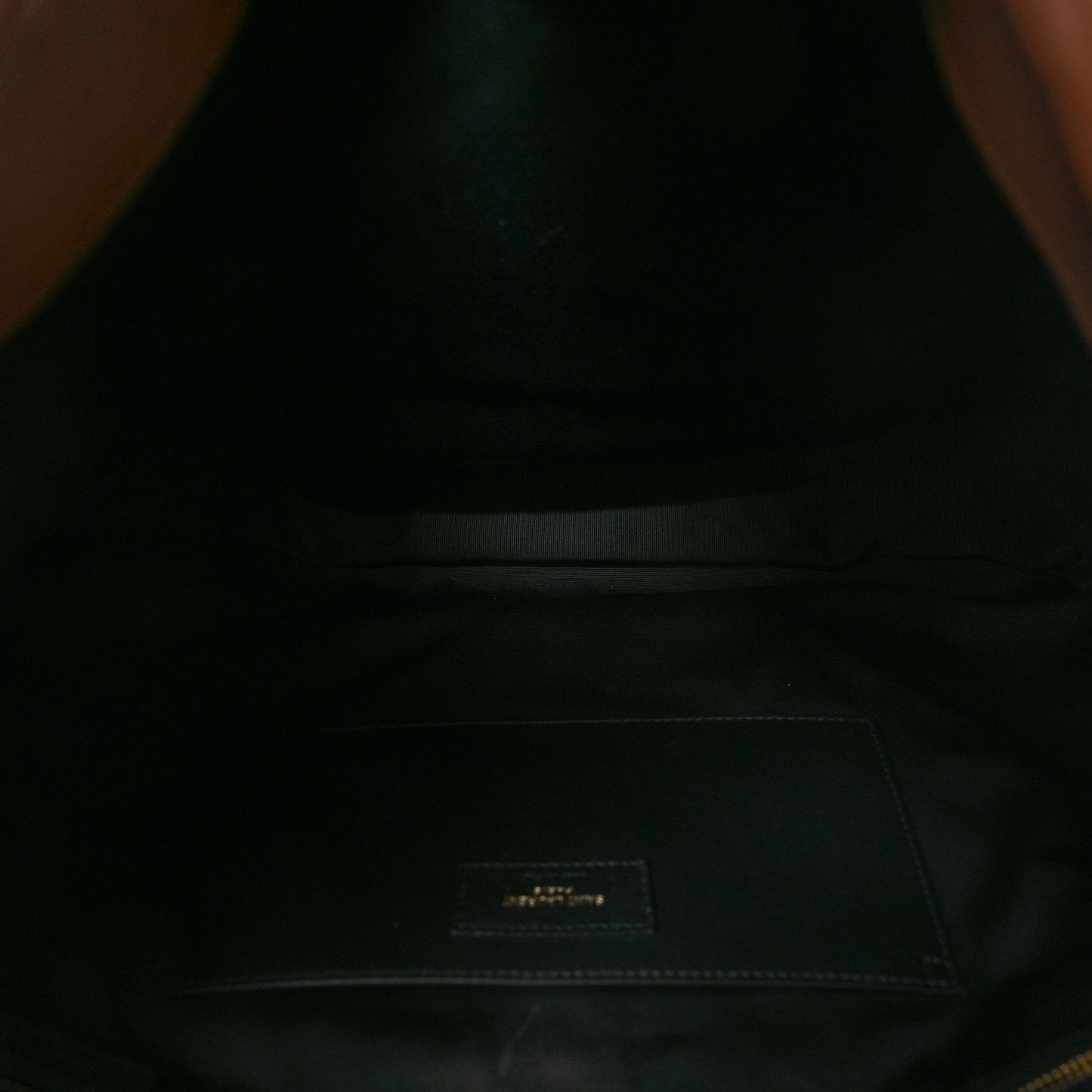 Dark interior lining of leather bag with small fabric logo patch