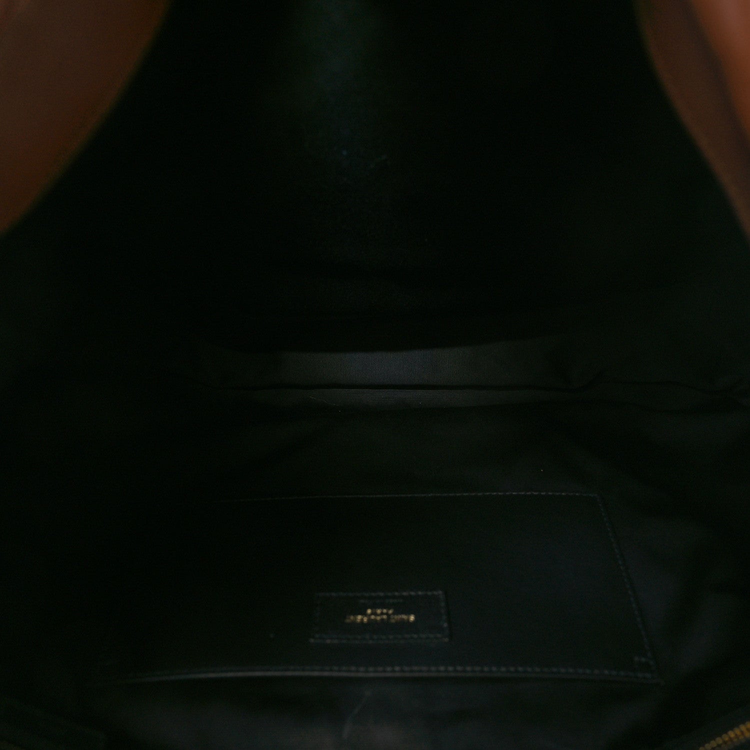 Dark interior lining of leather bag with small fabric logo patch